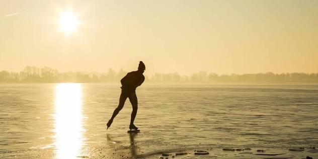Schaatser op natuurijs bij laagstaande winterzon